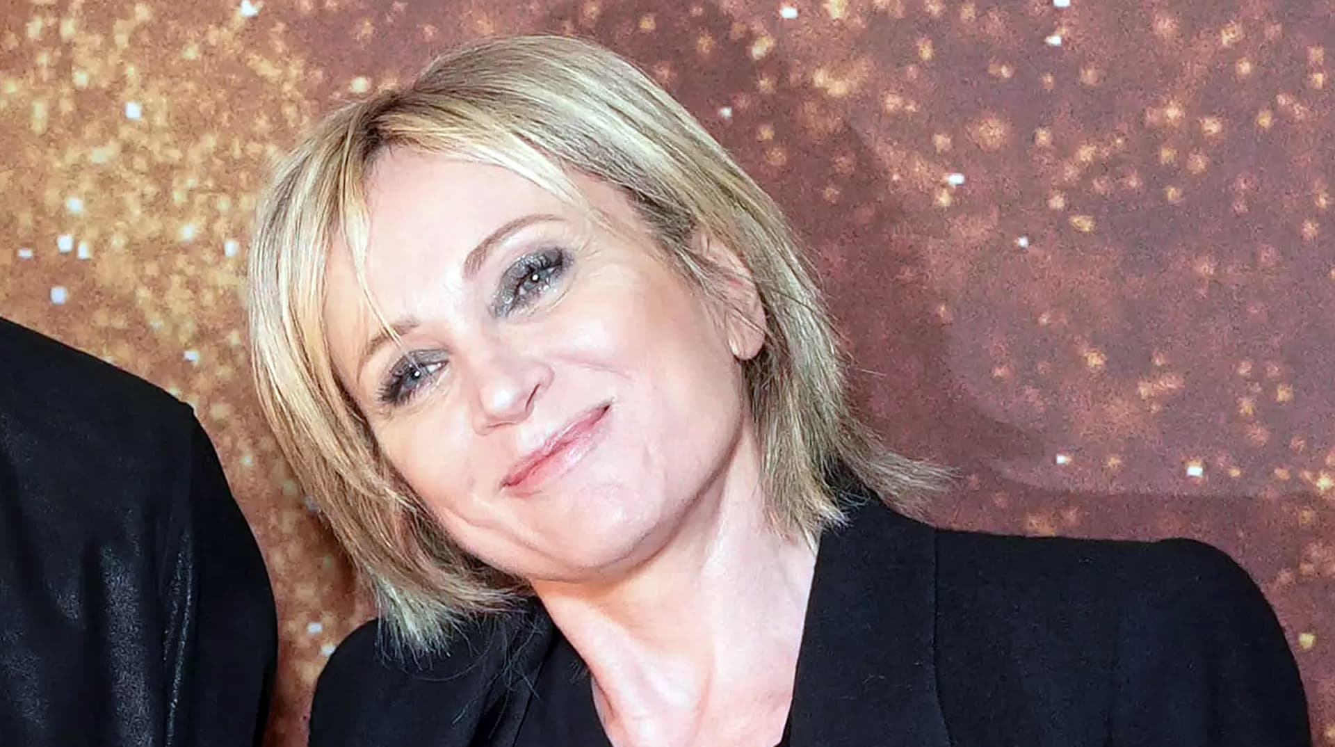 Patricia Kaas souriante, cheveux blonds et veste noire