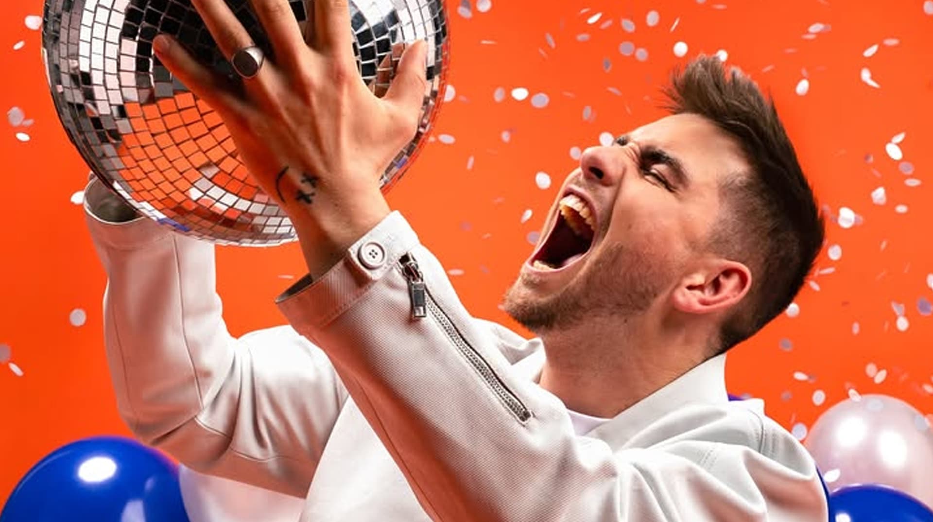 Julien Lieb en veste blanche crie, boule à facettes en main, sous les confettis