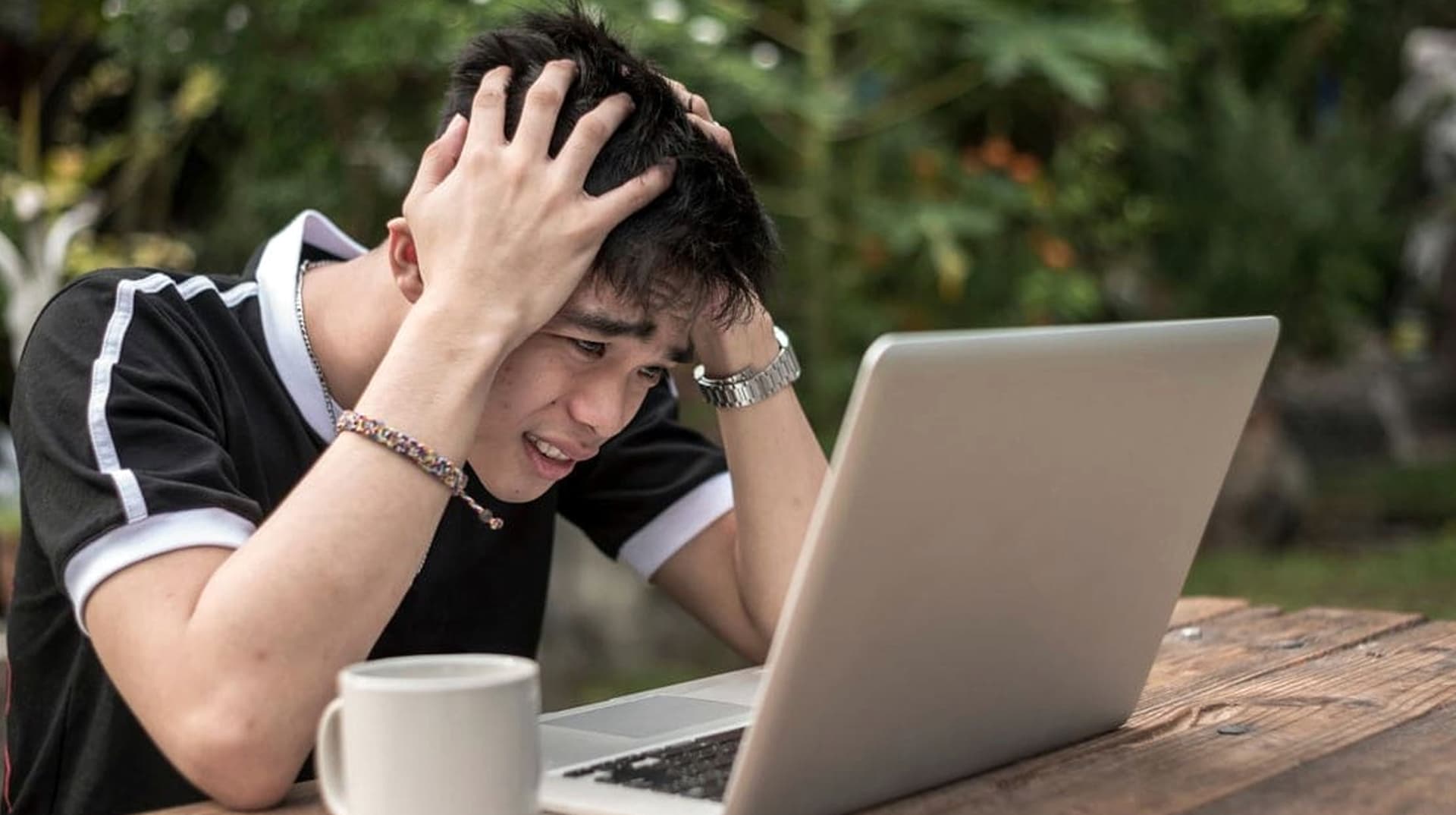 Un jeune homme se prend la tête devant son ordinateur portable