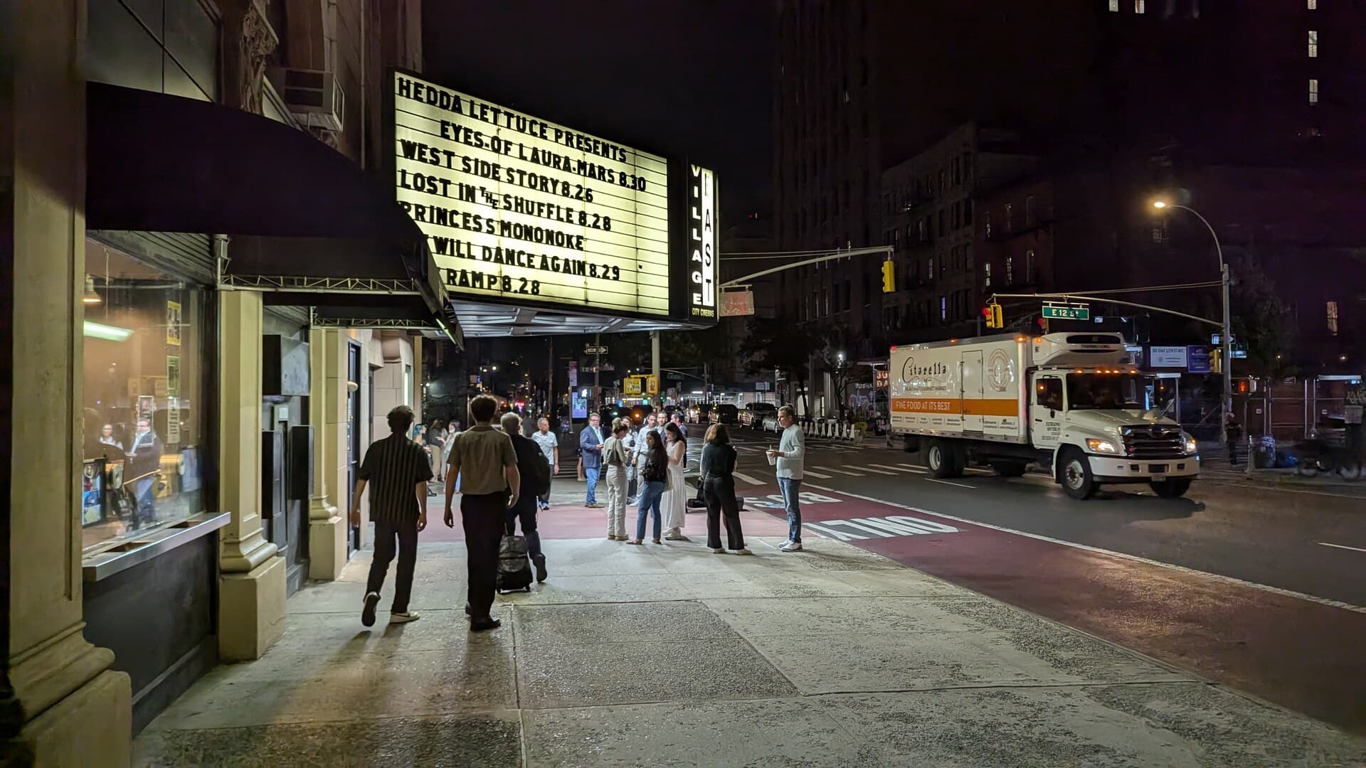 Une rue de nuit devant un cinéma à l’affiche éclairée