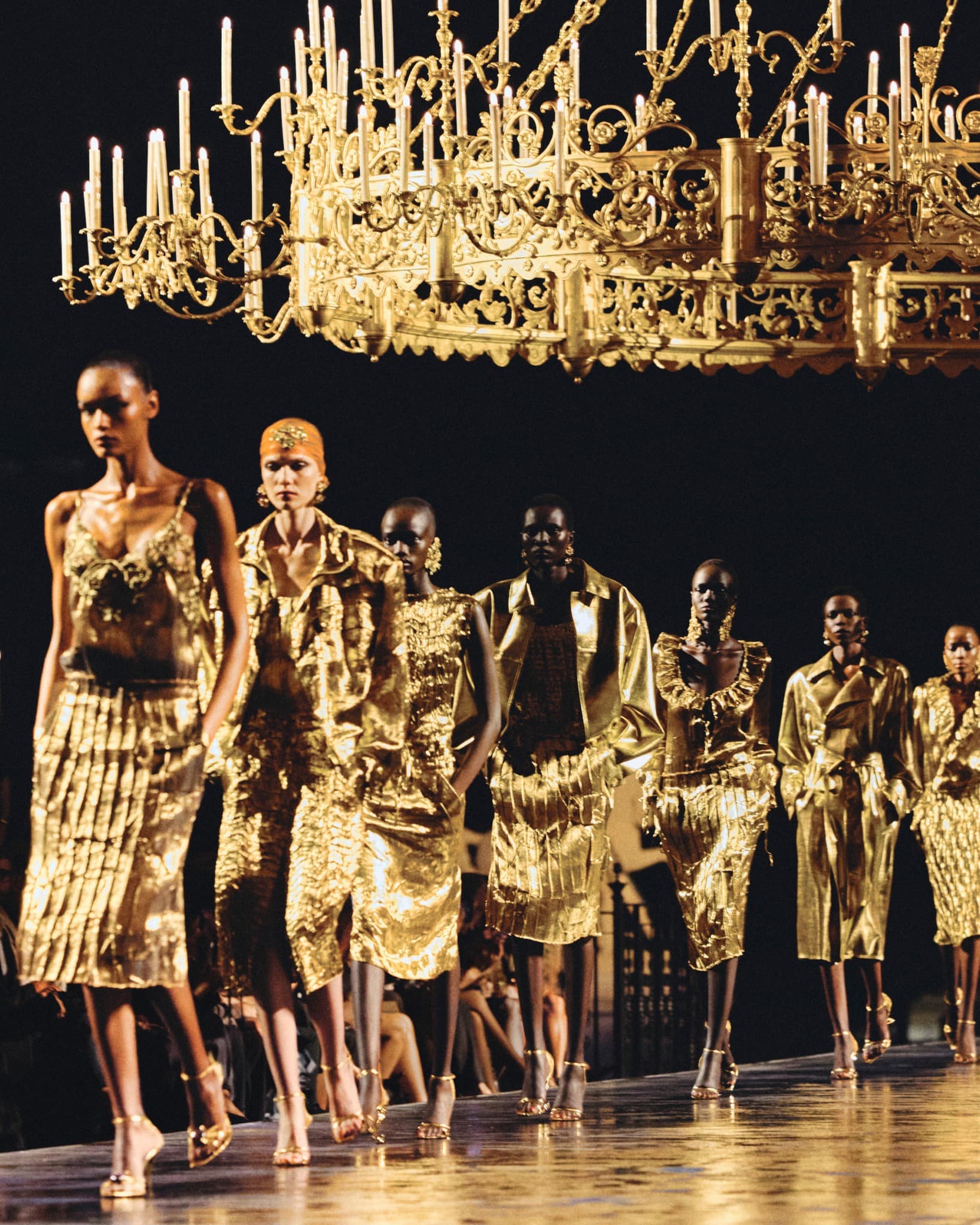 Mannequins Saint Laurent en robes et trenchs dorés sous un lustre doré
