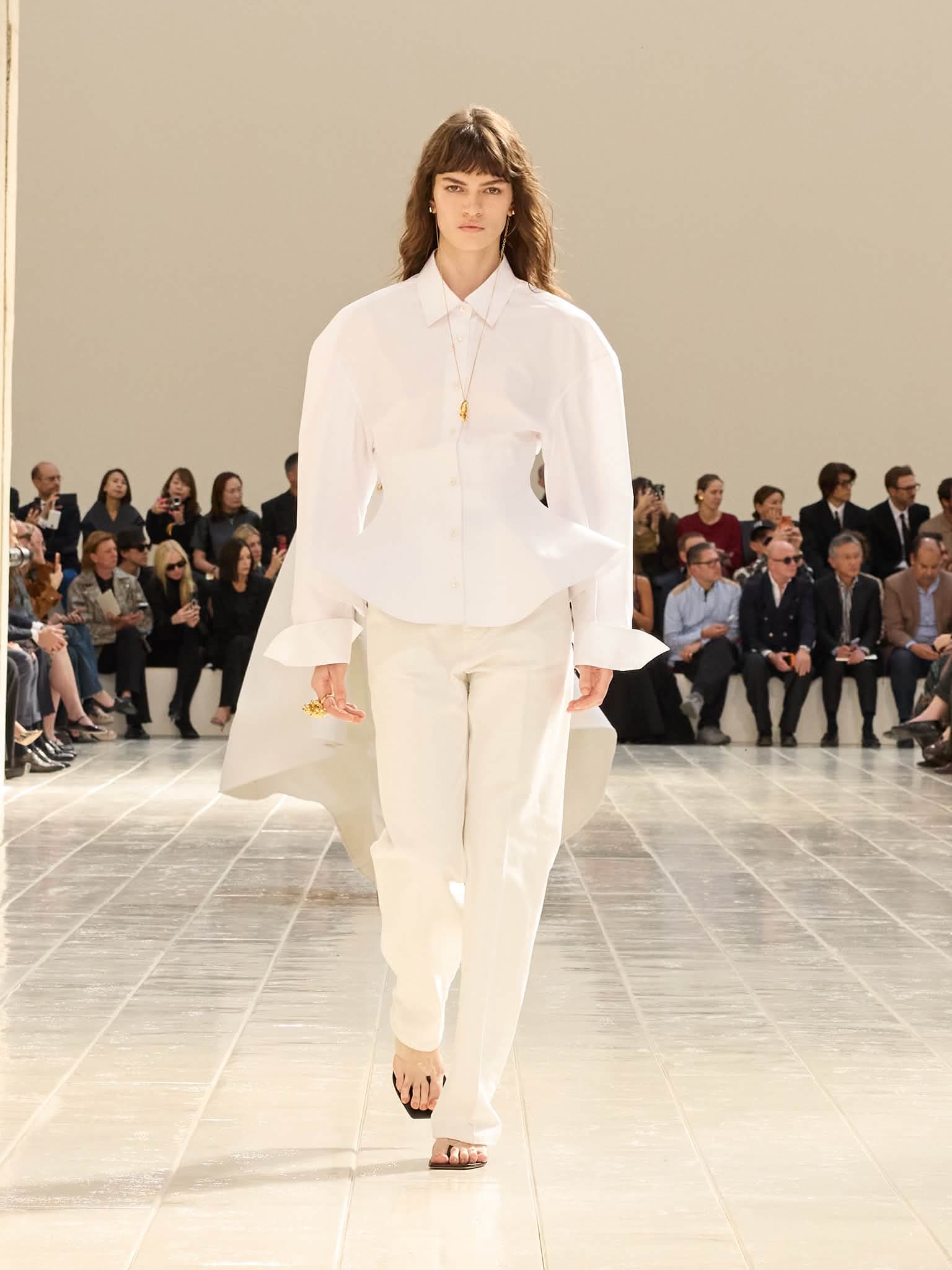 Mannequin Balenciaga en chemise blanche à basque corsetée et cape