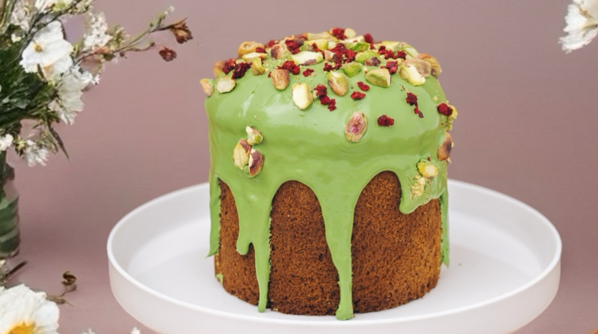 Paska nappée d’un glaçage vert à la pistache, parsemée de noix et de baies