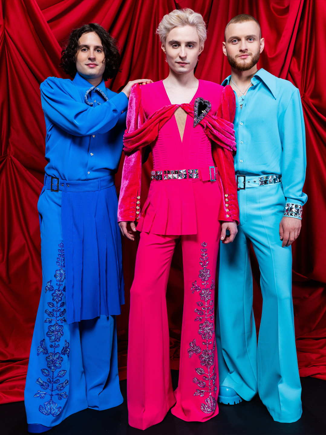 Ziferblat en costumes de scène bleu, rose et turquoise devant un rideau rouge