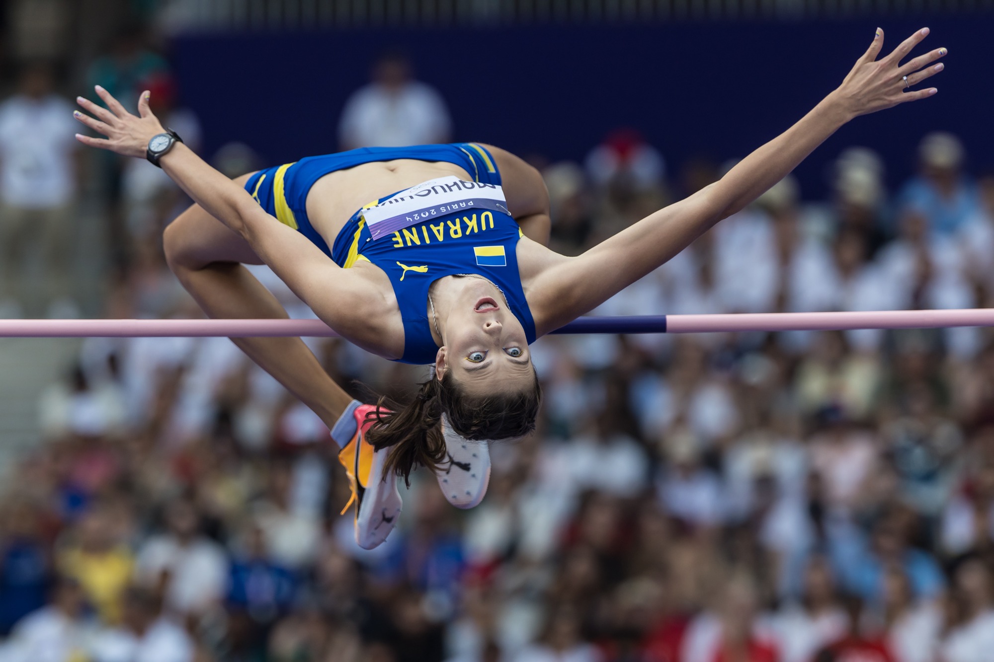 Yaroslava Mahuchikh en tenue bleue et jaune franchit la barre sur le dos aux Jeux olympiques de Paris