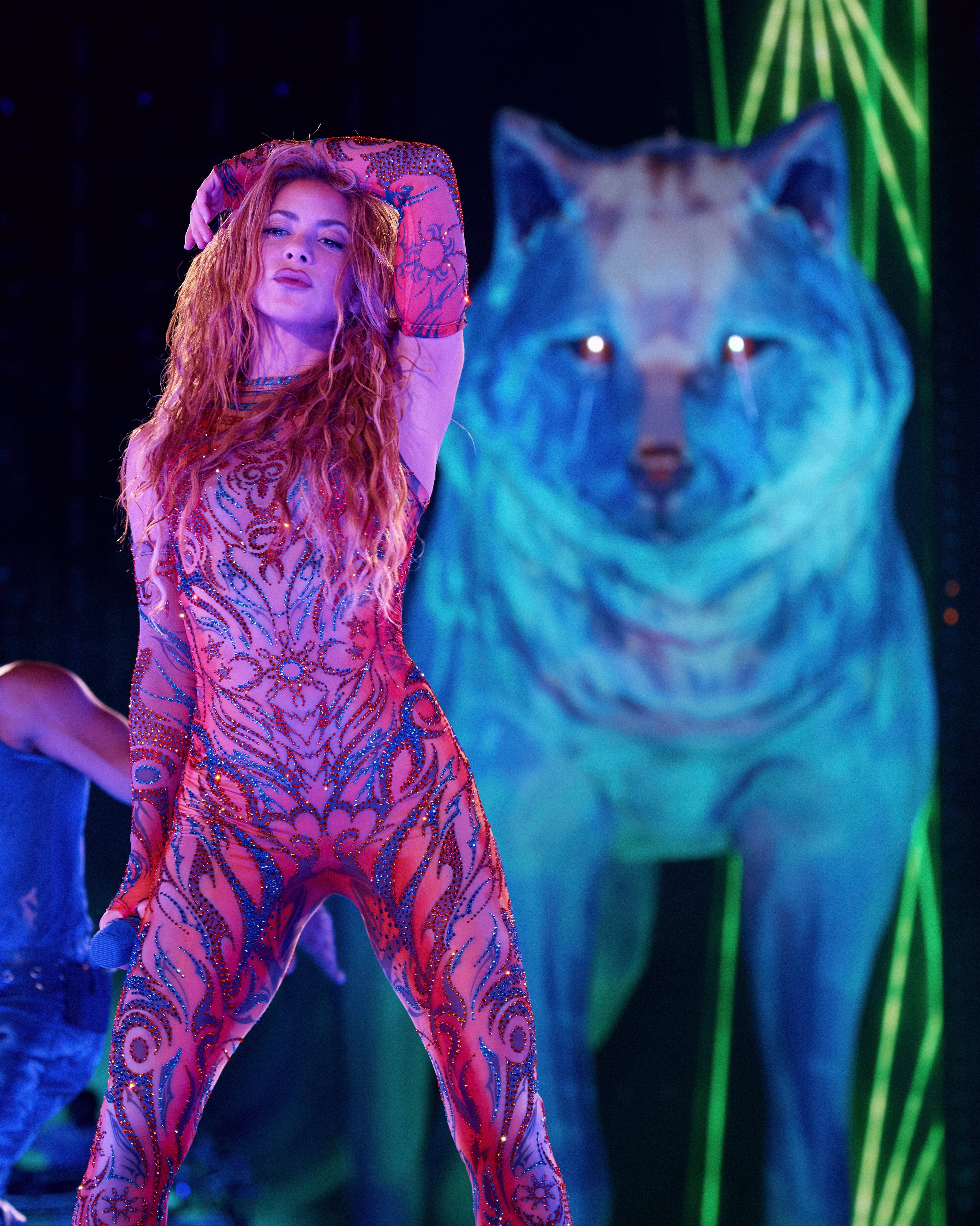 Shakira en combinaison brodée sur scène à côté d’un immense loup lumineux
