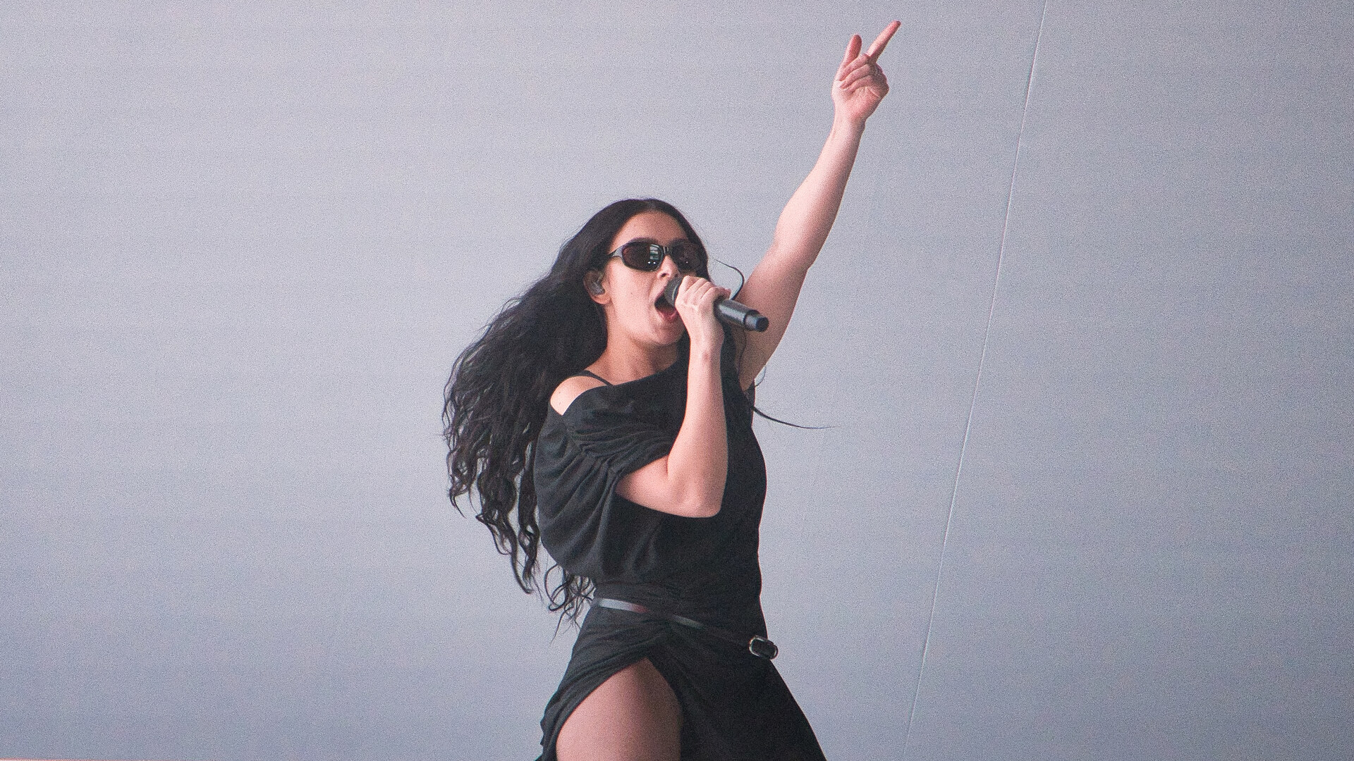 Charli XCX співає на сцені з мікрофоном